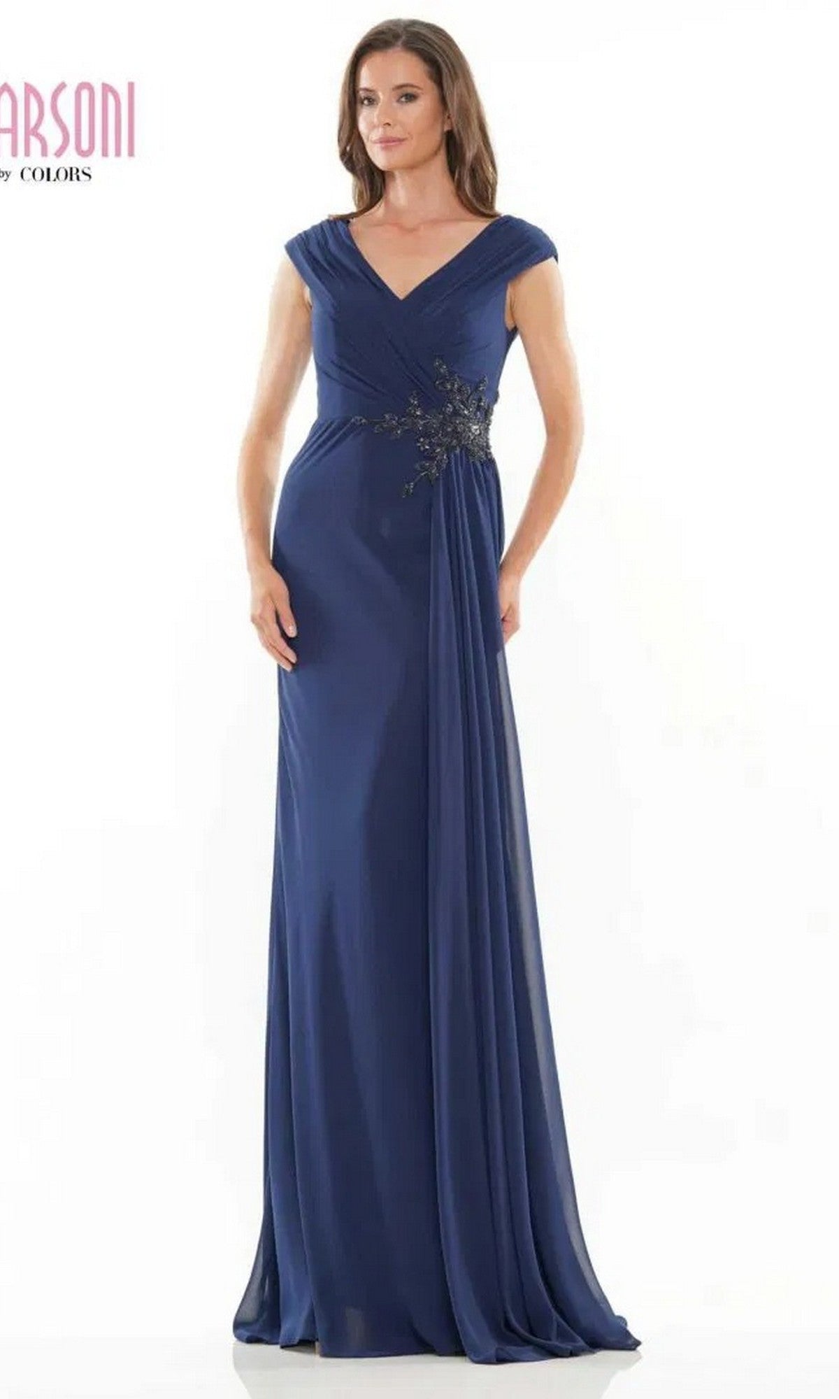 A woman in a navy Marsoni MV1080 long formal dress with cap sleeves, a V-neckline, and beaded waist applique stands against a plain white background.